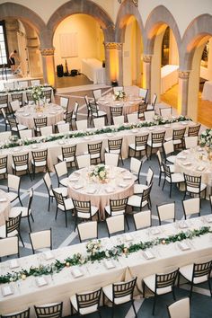 tables and chairs are set up in the center of an indoor banquet hall with white linens on them