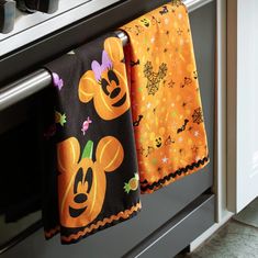 two kitchen towels hanging from an oven rack with mickey and minnie mouse faces on them