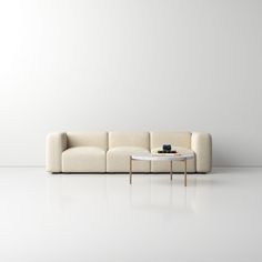 a white couch sitting next to a coffee table on top of a white floor in an empty room