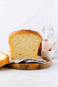 a loaf of bread sitting on top of a wooden cutting board next to a bottle of milk