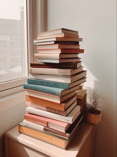 a stack of books sitting on top of a window sill