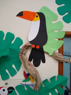 a paper plate toucan is on the wall next to some leaves and branches