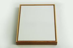 an empty wooden box with a mirror on the wall in front of it and a white background