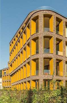 the building has many windows and balconies on each floor, along with plants growing in front of it