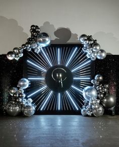 a clock that is surrounded by silver balls and balloons in the shape of a star