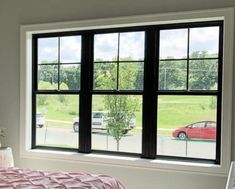 a bedroom with a bed and two large windows that look out onto the parking lot