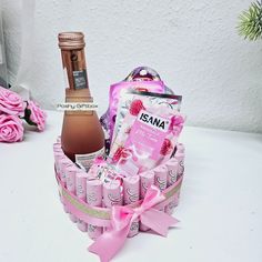 a bottle of wine and some chocolates in a basket with pink flowers on the table