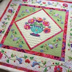 a quilted table topper with flowers and birds on it