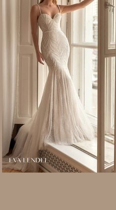 a woman in a wedding dress leaning on a window sill