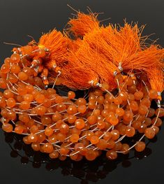 an orange beaded bracelet with tassels and beads on black background, closeup