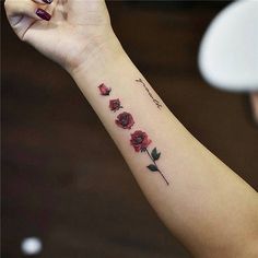 a woman's arm with red roses on it and the word love written in cursive writing