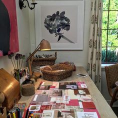 a wooden table topped with lots of crafting supplies next to a painting on the wall