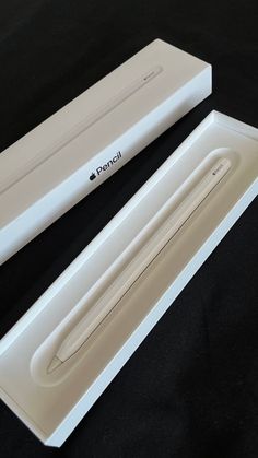 an apple pencil is sitting in a box on a black surface with its lid open