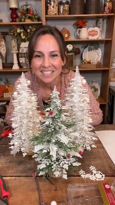 a woman sitting at a table with a fake christmas tree