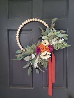 a wreath on the front door with flowers and greenery hanging from it's side