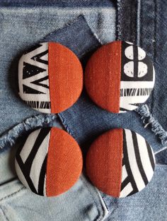 three buttons with different designs on them sitting in the back pocket of someone's jeans