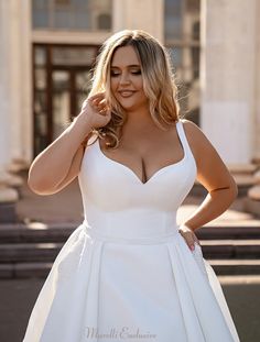 a woman in a white dress posing for the camera with her hands on her hips