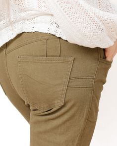 These pants are a stylish pair of mid-waisted jeans in an earthy olive green color. They feature a classic design with a modern twist, making them a versatile addition to any wardrobe. These pants are tailored to provide a flattering fit, with a high-rise waist that accentuates the wearer's natural waistline, creating a sleek and elongated silhouette. The front of the pants includes a traditional button and zipper closure, adding to their classic appeal. The trousers are equipped with functional front and back pockets, enhancing their practicality without compromising on style. The fabric appears to be a comfortable and durable material, suitable for both casual and more polished looks. One of the standout features of these pants is their wide-leg cut, which adds a touch of retro flair and Mid Waist Jeans, Olive Green Color, Polished Look, Flare Jeans, Green Color, Best Sellers, Classic Design, Olive Green, Wide Leg