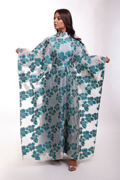 Turn heads in this mesmerizing floral Organza butterfly caftan dress, a true statement piece for the woman who loves to stand out. With its flowing butterfly sleeves and high neck design, this maxi-length beauty is perfect for black-tie events, luxurious resorts, or as an unforgettable wedding guest ensemble. Picture yourself twirling through a garden, or arriving at a fancy gathering with the vibrant floral gloss shimmering in the evening light. This dress is made for moments where elegance mee Elegant Floral Print Kaftan For Eid, Eid Party Dresses With Cape Sleeves, Floor-length Floral Print Kaftan For Spring, Elegant Floral Print Maxi Dress For Eid, Spring Floral Print Floor-length Kaftan, Spring Maxi Length Abaya, Long Kaftan For Spring Evening, Long Kaftan For Evening And Spring, Long Kaftan For Evening In Spring