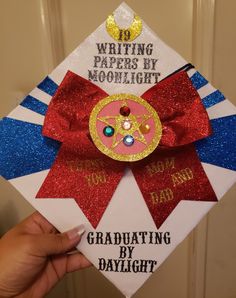 a hand holding up a graduation cap with writing papers by moonlight written on the front