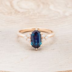 a ring with an oval cut blue sapphire surrounded by small white diamonds on a wooden surface