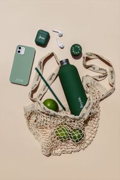 the contents of a sports bag laid out on top of a white surface, including an apple, water bottle and headphones