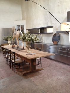 a large wooden table sitting in the middle of a kitchen next to a stove top oven