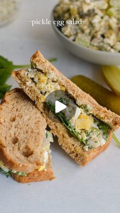 a sandwich cut in half sitting on top of a white plate next to a bowl of salad