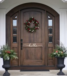 two large planters with wreaths on the front door