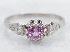 Crafted in stunning white gold, this ring features a vibrant round-cut pink sapphire flanked by sparkling diamond accents. Elevate your style with this elegant piece, perfect for any occasion! Metal: 10K White Gold Gem: Pink Sapphire .49 Carats Gem Measurements: 4.6 mm, Round Accents: 4 Diamonds totaling .14 Carats, I in Clarity, H-I in Color Ring Size: 7.50 SKU #: A42906 Each piece has been identified and graded by a Graduate Gemologist who has been certified by the Gemological Institute of America (GIA). We have six brick-and-mortar storefronts in Maine, Massachusetts, and New Hampshire and have been in business for over 25 years! Please visit our Shop's About Page or our website for more information about our jewelry. For questions about diamond grading, we recommend the  Gemological In Formal Pink Diamond Ring In Platinum, Fine Jewelry Pink Diamond Ring In Platinum, Pink Sapphire Platinum Ring Gift, Pink Sapphire Diamond Ring With Center Stone, Pink Brilliant Cut Sapphire Ring In Platinum, Pink Sapphire Ring With Brilliant Cut In Platinum, Pink Sapphire Brilliant Cut Platinum Ring, Pink Platinum Diamond Ring For Anniversary, Formal Pink Sapphire Ring In Platinum