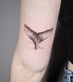 a small whale tail tattoo on the arm