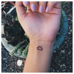 a woman's wrist with a small tattoo on it