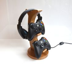 two video game controllers sitting on top of a wooden stand