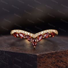 a gold ring with red and white stones on top of a wooden table next to a black background