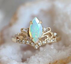 an opal and diamond ring sitting on top of some crystals