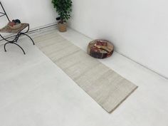 a white room with a rug, chair and potted plant on the floor next to it