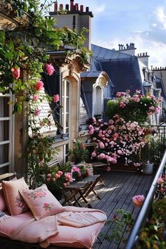 a balcony with lots of pink flowers and plants on the outside, along with wooden flooring