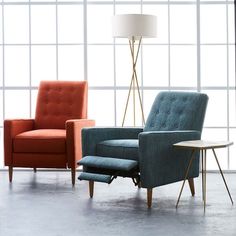 two chairs and a table in an empty room with large windows, one is orange and the other is blue