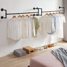 clothes are hanging on the rail in front of a bed