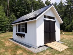 a small white shed with a black roof