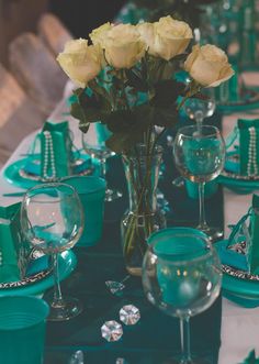 the table is set with white roses in a vase and green napkins on it