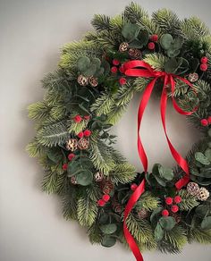 a christmas wreath with red ribbon and pine cones