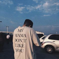 a man standing in the middle of a parking lot wearing a white shirt that says, my mama don't like you