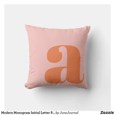 a pink pillow with an orange letter on it