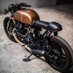 a brown motorcycle parked in a garage next to a cement wall and floor with no one on it