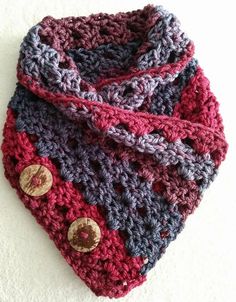 a crocheted cowl with buttons on the end and a scarf around it