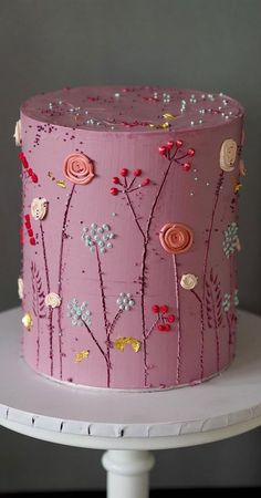 a close up of a cake on a table with pink frosting and colorful flowers