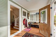 the entry way to a home with wood floors and white walls, has a wooden door that leads into another room