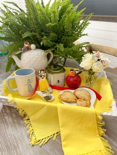 a table topped with plates and cups filled with food next to a potted plant