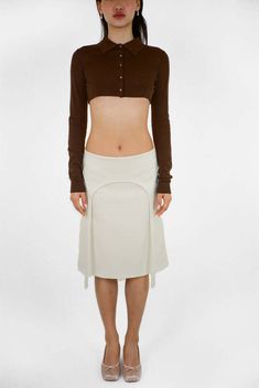 By sandy liang    knee length skirt in bone  garter strap detail at front  concealed zipper at back  made in nyc    size  length  waist  hip  0 22 1/2" 30"  37 1/2"   2 22 3/4" 31"  38 1/2"   4 23" 32"  39 1/2"   6 23 1/4" 33"  40 1/2"   8 23 1/2" 34"  41 1/2"   10 23 3/4" 35"  42 1/2"   12 24 1/2" 36 1/2"  44" Cream Fitted Asymmetrical Skirt, Fitted Cream Asymmetrical Skirt, Fitted Cream Midi Skirt, Fitted Beige Asymmetrical Skirt, Fitted Asymmetrical Beige Skirt, Fitted Cream Mini Skirt For Fall, Beige Fitted Asymmetrical Skirt, Cream Fitted Midi Skirt, Garter Skirt